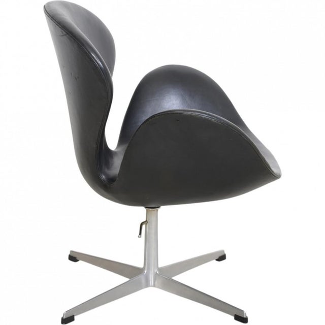 Arne Jacobsen Swan chair upholstered in black leather, and with an aluminium base. The chair is from 1964 and appears with...