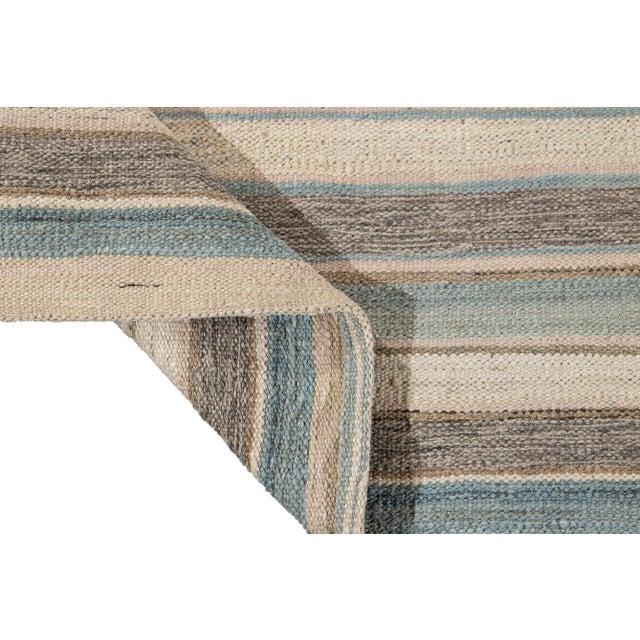 Beautiful modern flat-weave Kilim hand-knotted wool rug. This rug has a field of beige, blue, and brown color in a...