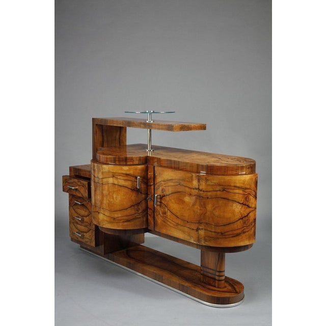 Art Deco period bar cabinet in walnut and walnut veneer opening to two doors and four drawers. Chrome-plated base and...