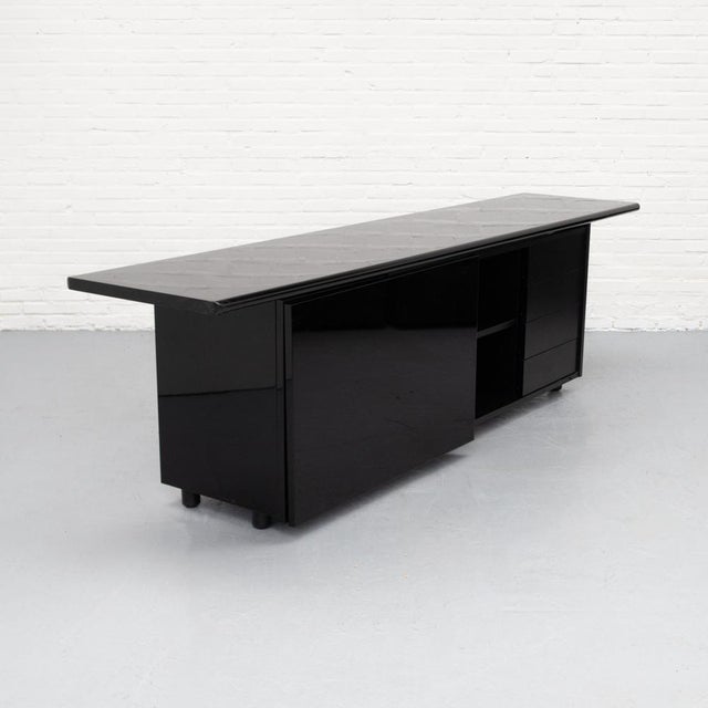 Large Italian 1980s sideboard finished in a deep high-gloss lacquer, creating a subtle reflective surface. The elongated,...