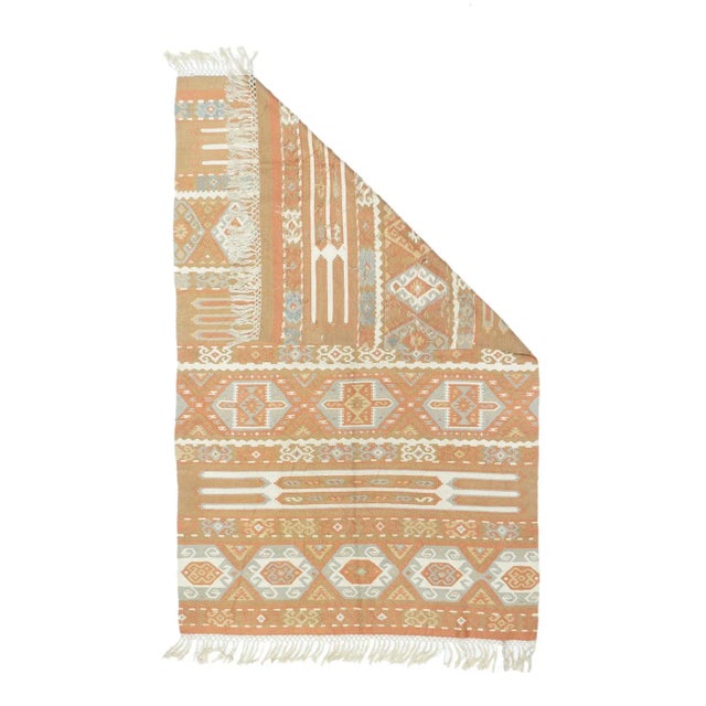 In a standard slit weave, this pileless, flatwoven scatter shows a five echelon layout of hooked lozenges within taller...