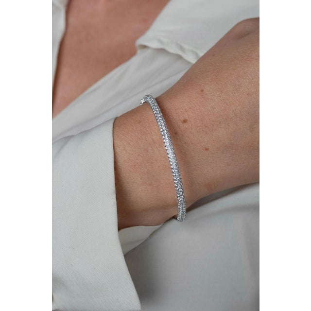 Micro pave set round brilliant cut natural diamonds mount this stunning 18 karat white gold bangle bracelet. Handmade with...