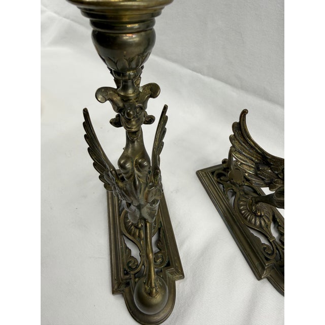 Pair Brass Late 19th Century Neoclassical Chimera candlesticks. Styled Avian head holding a candle cup, Slender torso with...