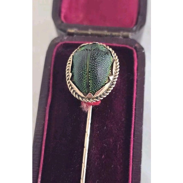 A distinctive antique 9ct yellow gold novelty stickpin, featuring an Egyptian scarab beetle as its central decorative...
