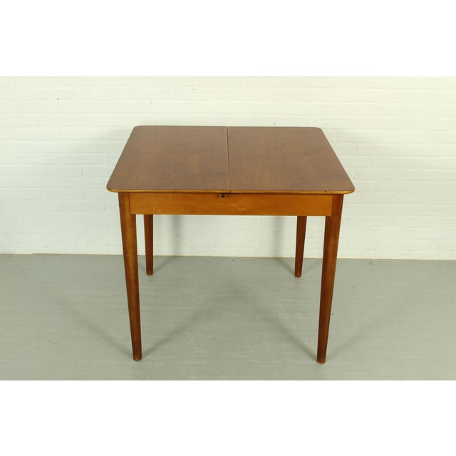 Elegant drop-leaf table stamped 1958, likely produced by Dutch design house Pastoe. with clean lines and a warm wood...