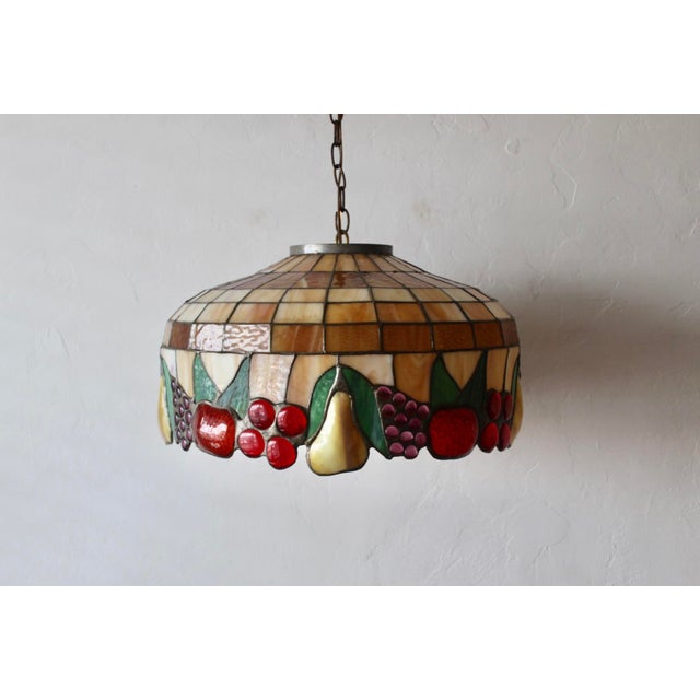 Tiffany-style stained glass pendant light featuring a fruit and leaf motif (such as the Meyda Tiffany Fruit pendant...