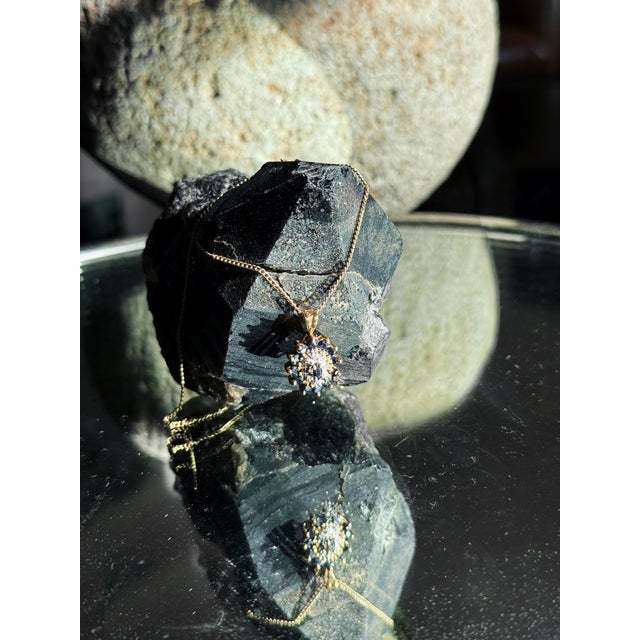 A striking vintage cluster pendant featuring natural blue sapphires and diamonds in a dimensional floral arrangement. The...