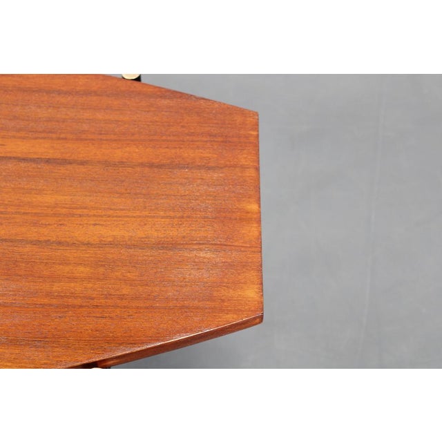 Italian coffee table from the 1970s featuring a veneered teak top desk and a stylish base of black metal legs with brass...