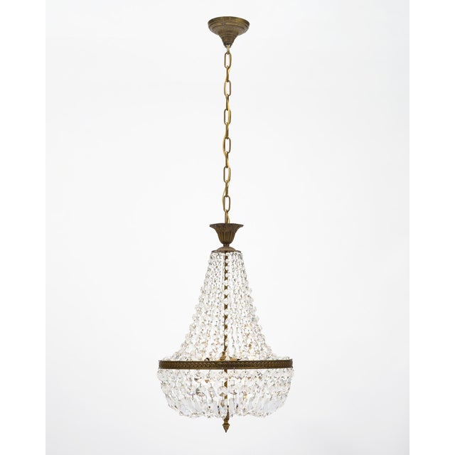 Antique chandelier from France made with cut crystal elements of cabochons and pendants. They are displayed on a brass...