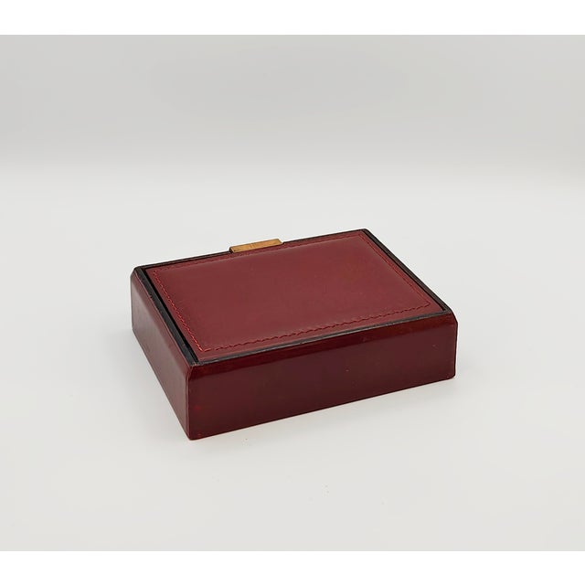 1970s French Hermès-style burgundy leather playing cards box with brass accents. Interior compartments hold two (2) decks...
