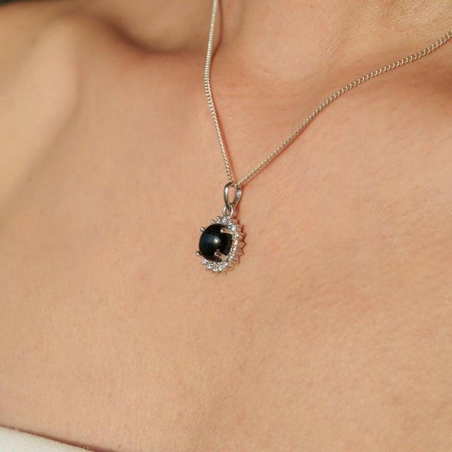 Crafted in 925 sterling silver, this stunning black star gemstone pendant features an 11.55 carat center stone with a...