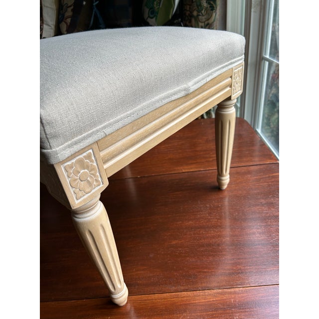 A Belgian linen upholstered carved wooden legged stool.