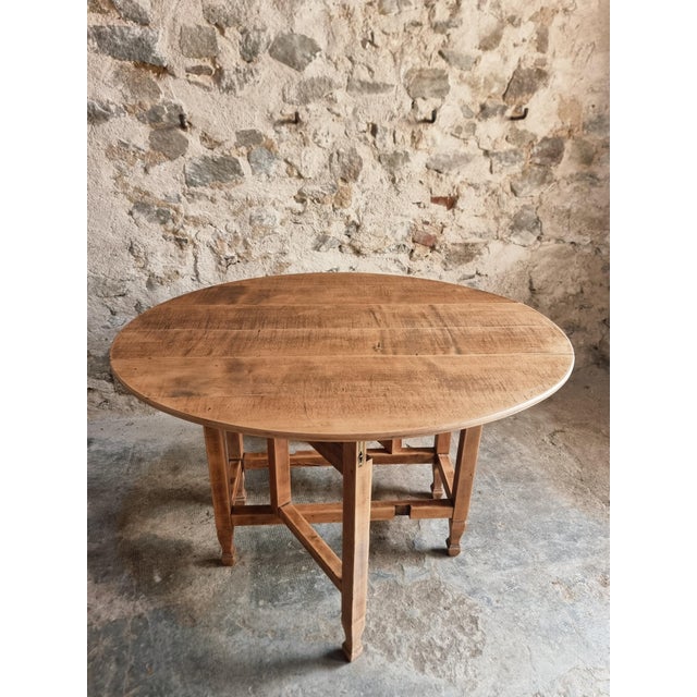 Vintage French gateleg table dating from approximately 1930–1950, featuring an oval top with folding drop leaves on both...