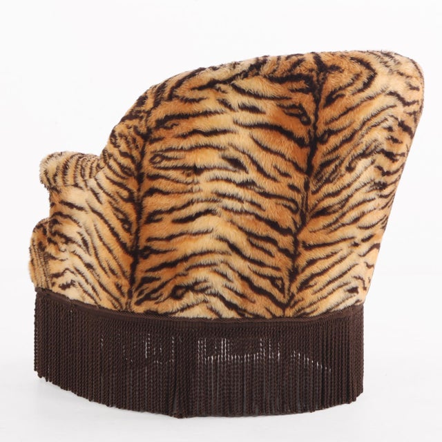 A charming French lounge chair featuring a rounded back and arms all upholstered in a striking faux tiger fabric. The bold...
