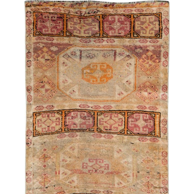 This mid-20th-century Turkish Anatolian runner presents a distinctive compartmentalized design arranged across a warm...