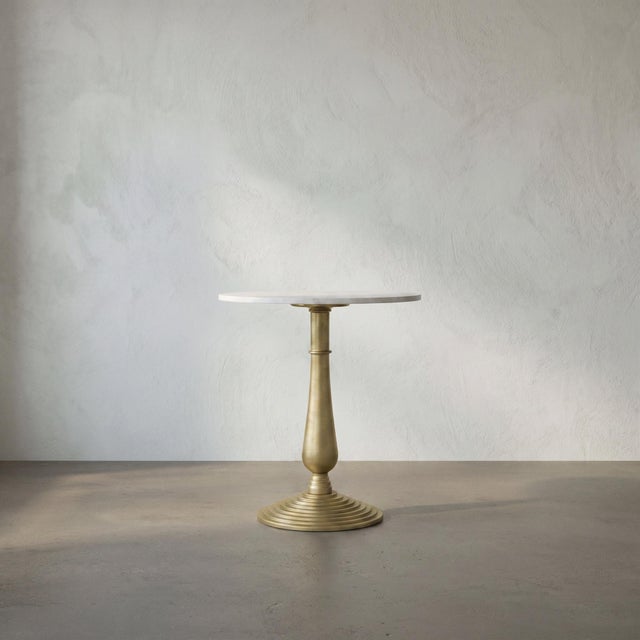 Two elemental materials meet in this quietly dramatic accent table. The base is formed of cast iron with a soft gold...