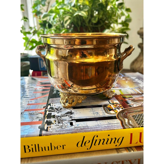 This vintage brass cache pot will add a bit of Hollywood Regency charm to any setting. It stands on 3 Art Nouveau style...