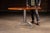 Round hardwood café or dining table featuring a thick, solid-wood top with a warm, medium-brown finish set over a welded...