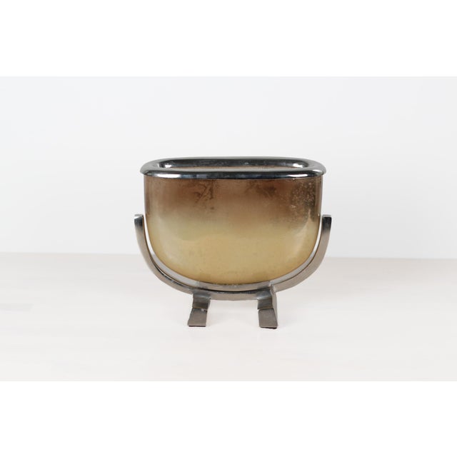 Mid-century sculptural jardinière featuring an oval glass vessel with a graduated smoked gold finish, suspended within a...