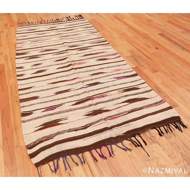 Abbreviated stripes and birdlike accents rendered in a stark combination of walnut brown, ivory and splashy colors...