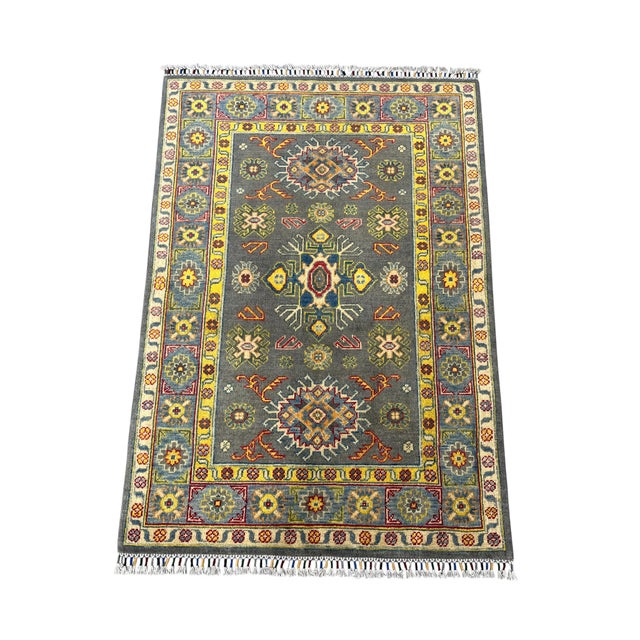 A charcoal gray field carries a balanced geometric design in soft blue, gold, burgundy, and cream. Two bold medallions,...