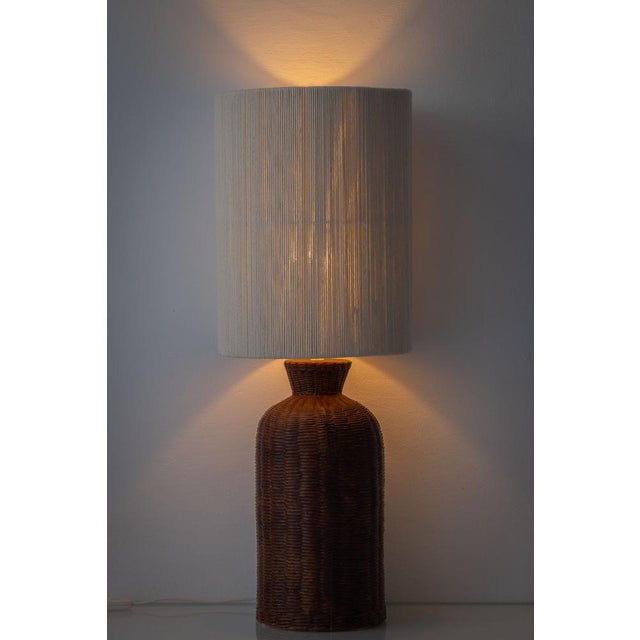 A large vintage ceramic table lamp with a trompe l’oeil wicker (rattan-style) basketweave base in warm brown glaze, paired...