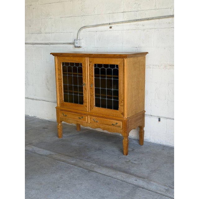 This oak display cabinet in style of Henning Kjærnulf combines two glass-front doors with two lower drawers. Sculpted...