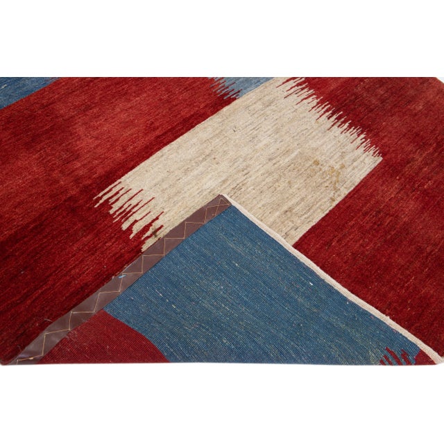 Beautiful modern Gabbeh-style hand-woven wool rug with a red color field. This piece has blue and beige accents in a...