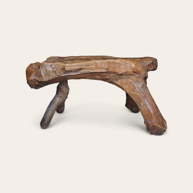 Hand-carved folk art stool in solid wood with a natural live edge seat and sculptural tripod base. One leg is peg-joined...