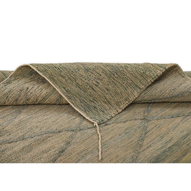A soft diamond lattice traces its way across this handwoven rug, its neutral taupe ground carrying quiet hints of sage and...