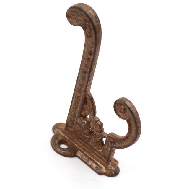 Antique Eastlake style hook made of cast iron with a painted tan distressed finish. The original mounting screws are not...