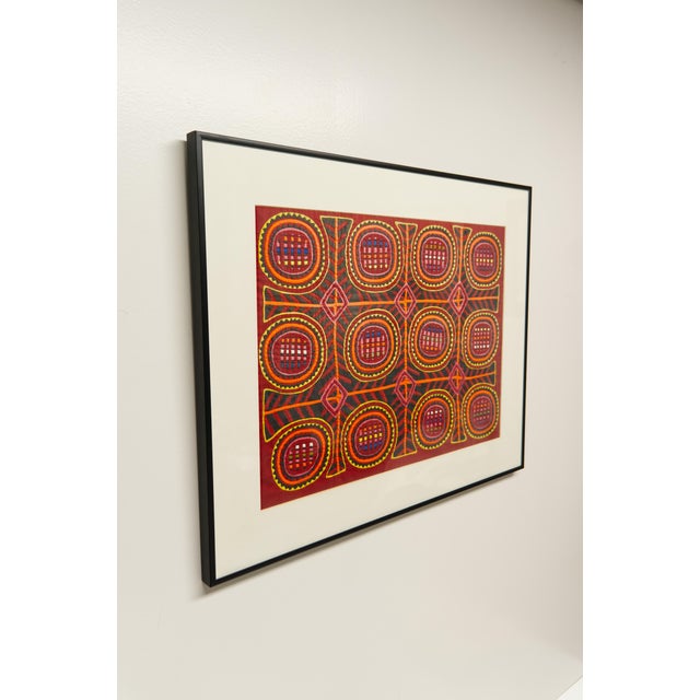 A framed textile mola art hand crafted by the Kuna women of San Blas, Panama. White mat board and black metal frame....