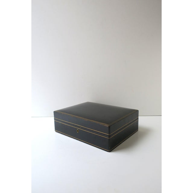 An Italian black leather jewelry box with gold tooling, in the Modern style, mid‑20th century, Italy. Crafted in smooth...