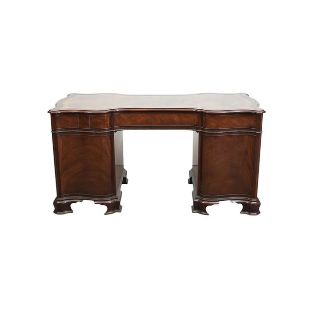 The Serpentine Front Baker Mahogany Leather Top Pedestal Writing Desk is a vintage piece with an antique brass handle...