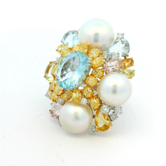 A vibrant and dimensional cocktail ring showcasing a richly layered cluster of aquamarines, cultured pearls, yellow...