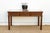 A long Chinese center table in dark walnut-brown wood, built to be seen from every side. A carved lattice panel sits...