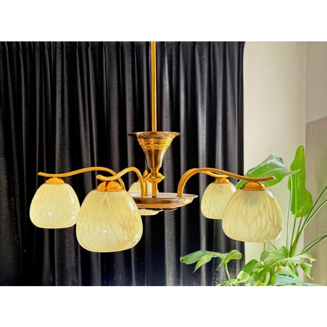 This Art-Deco pendant lamp with 5 glass spheres is truly a feast for the eyes! The elegantly designed chandelier in brass...