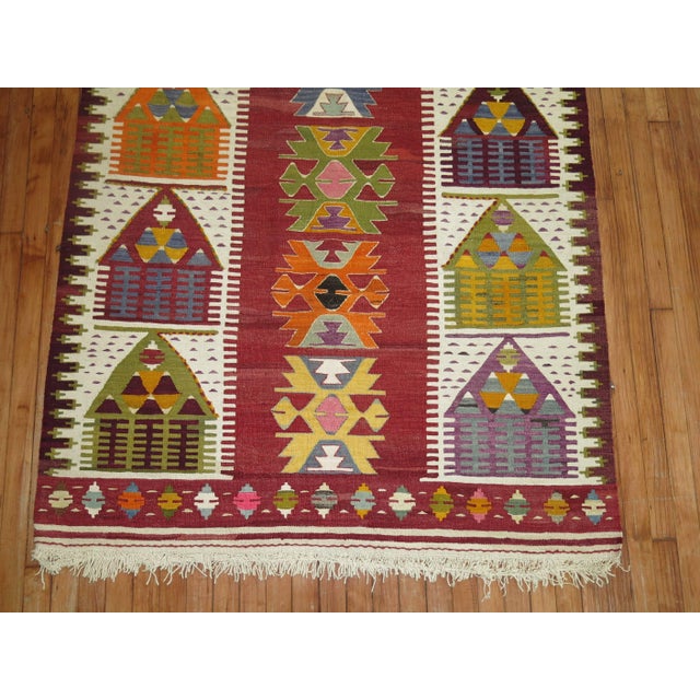 A vintage turkish Kilim flat-weave with a directional motif of small homes.