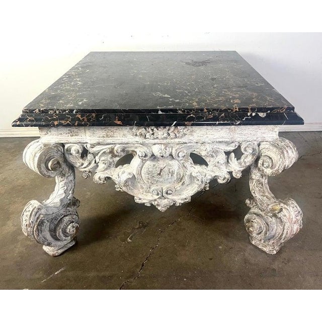 Monumental rectangular, ornate Rococo style coffee table featuring a dark, polished marble top with natural veining and...