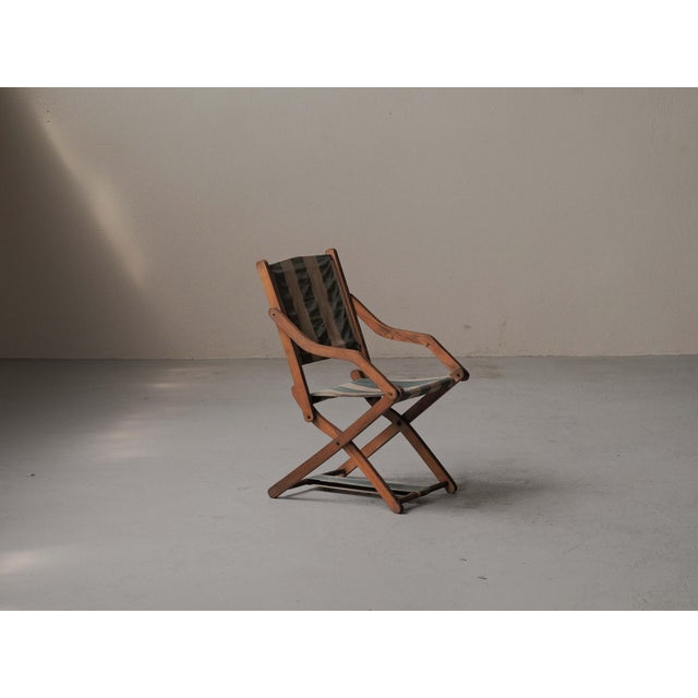 Elegant folding armchair, dating from the early 1900s, is a beautiful example of European campaign-style furniture,...