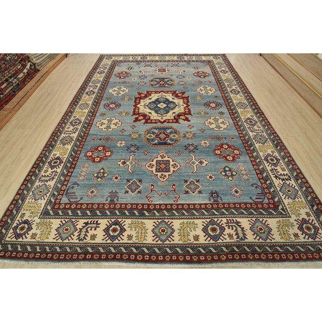 A tribal Caucasian Kazak rug hand-knotted with fine wool on a cotton foundation. This oriental rug features a central...