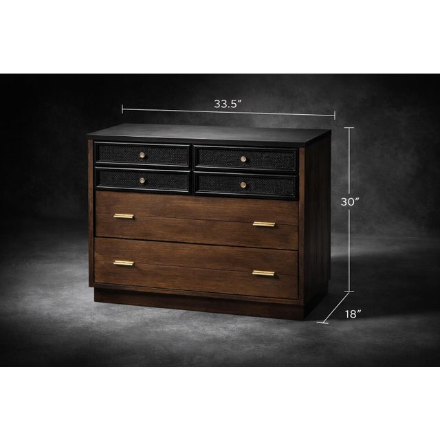 A compact vintage mid-century dresser featuring black cane drawer fronts, warm walnut veneer, and brass hardware. Its...