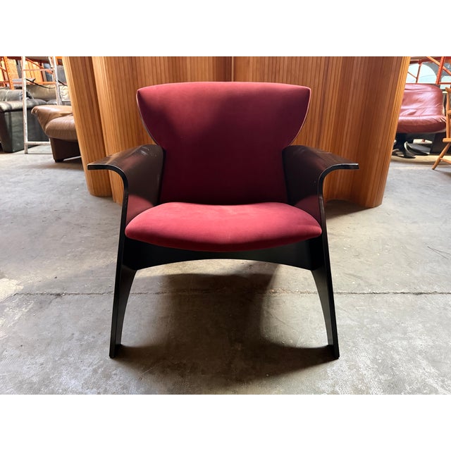 Conspicuous 80s black armchair with burgundy velvet upholstery.