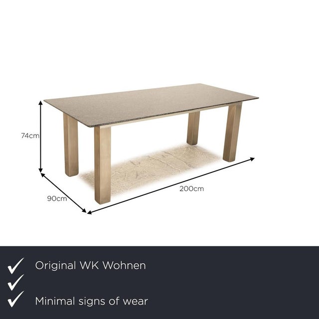 The dining table from WK Wohnen consists of a granite top and stands on silver metal feet. It is characterized by its...