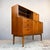 Constructed with teak veneer. The upper section features sliding glass doors enclosing a display cabinet with fixed...