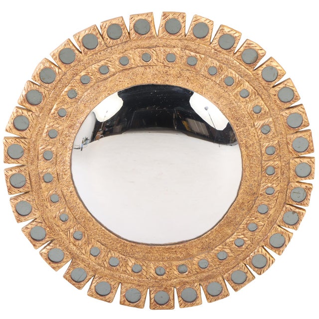 The textured gray glass circles are inset into a gold frame arranged in a simple geometric and sunburst pattern, a...