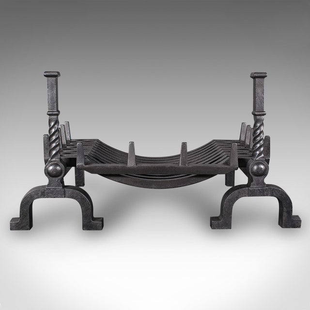 This is an antique fireplace set. An English, cast iron fire basket with andirons, dating to the Edwardian period, circa...