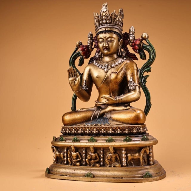 This vintage devotional statue is crafted from gilt bronze or copper and depicts a seated Buddha, likely representing...