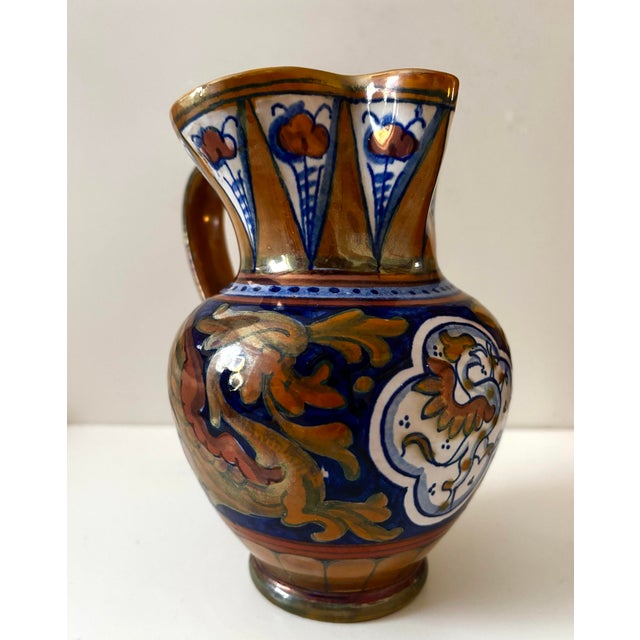 A richly decorated Italian majolica pitcher featuring a dramatic griffin or dragon motif rendered in deep cobalt blue,...