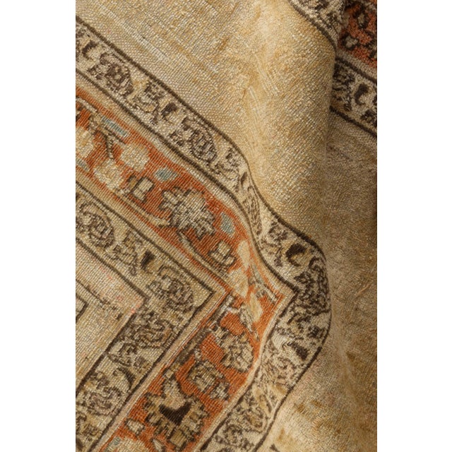 An early 20th century Mashad Persian rug, the camel field with an overall design of floral motifs, feathery leaves and...